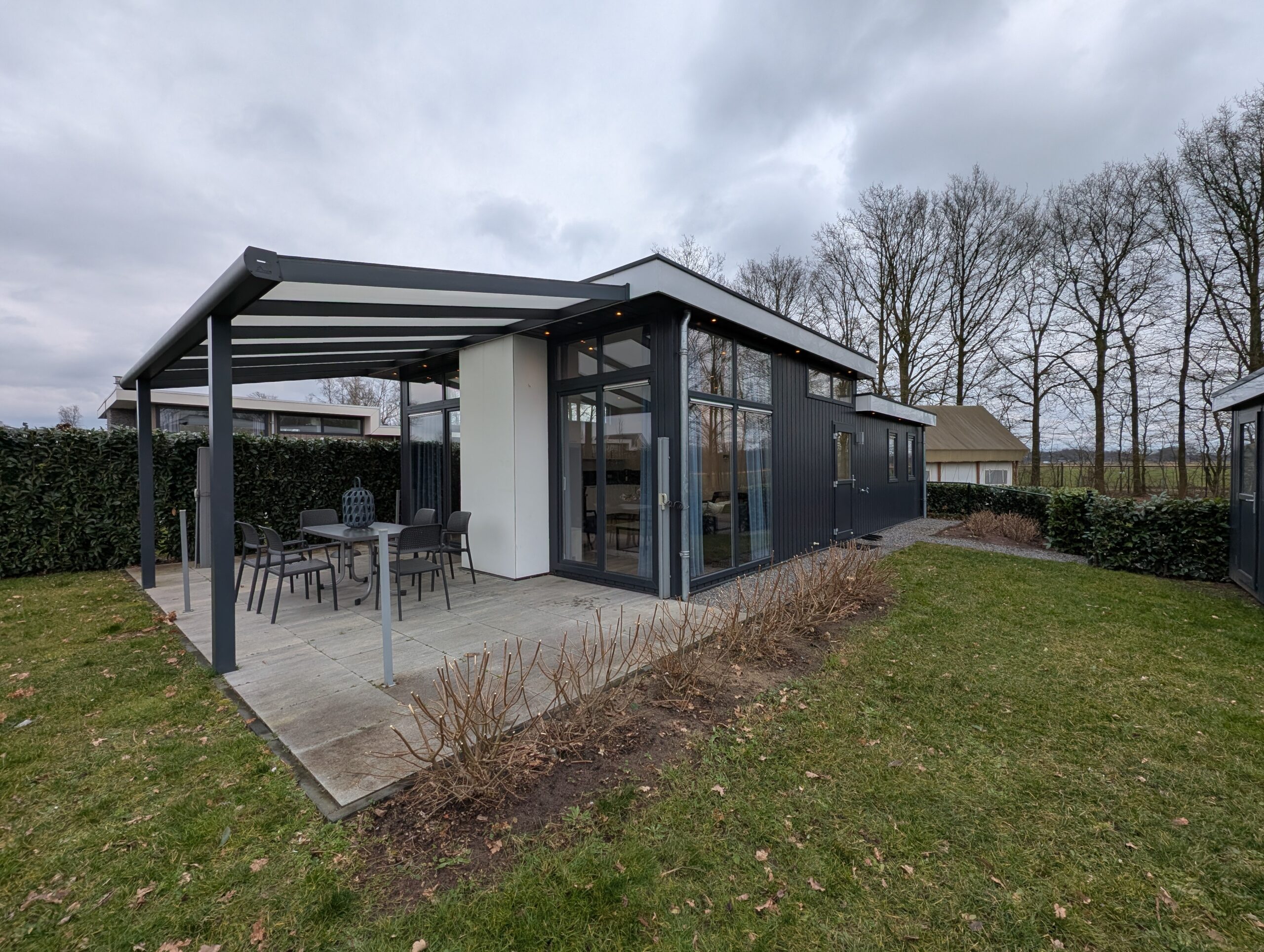 Een foto schuin gericht op het vakantiehuis vanuit de achtertuin