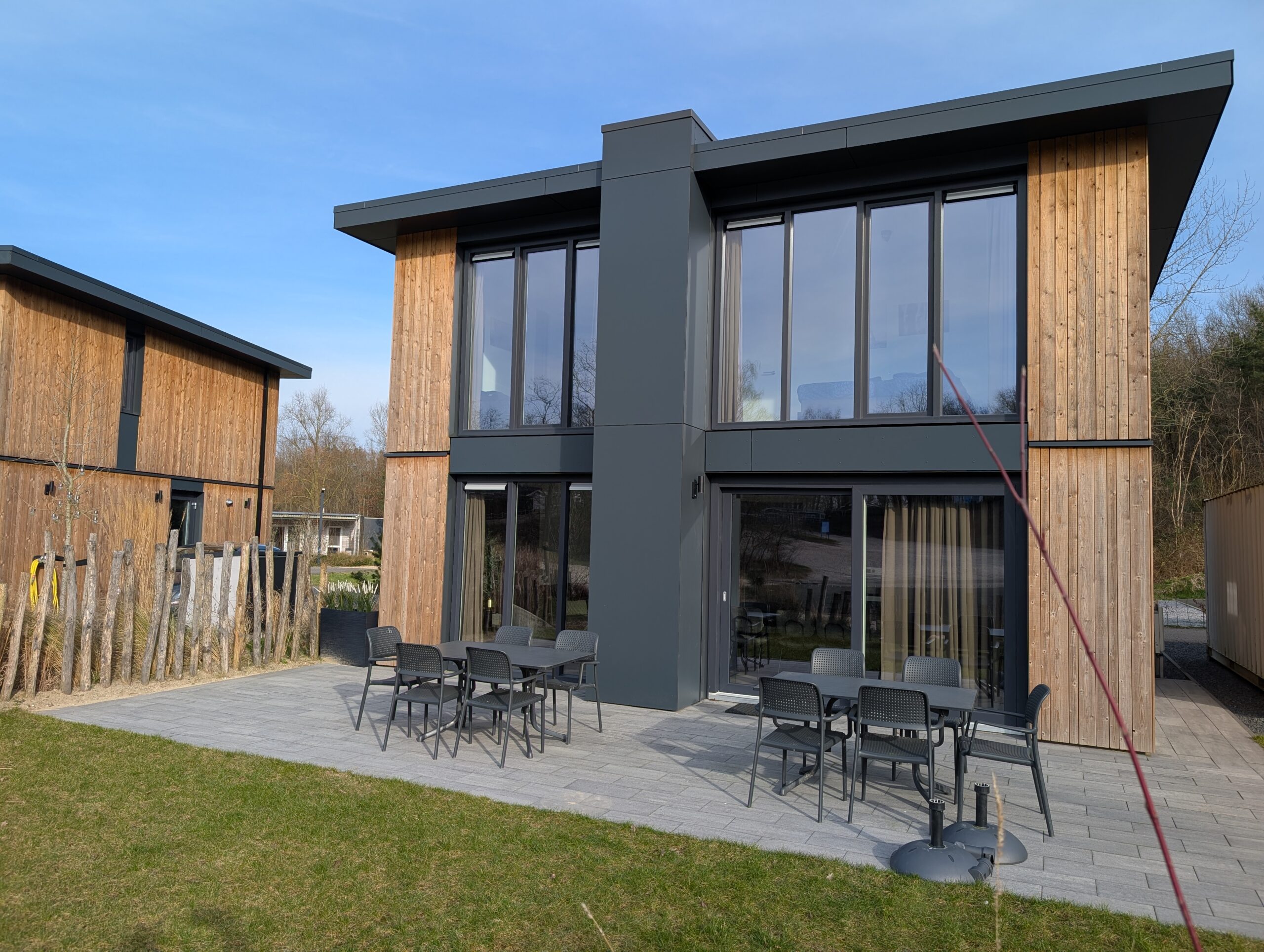 Een foto van de achterkant van het vakantiehuis met twee tafels en tien stoelen