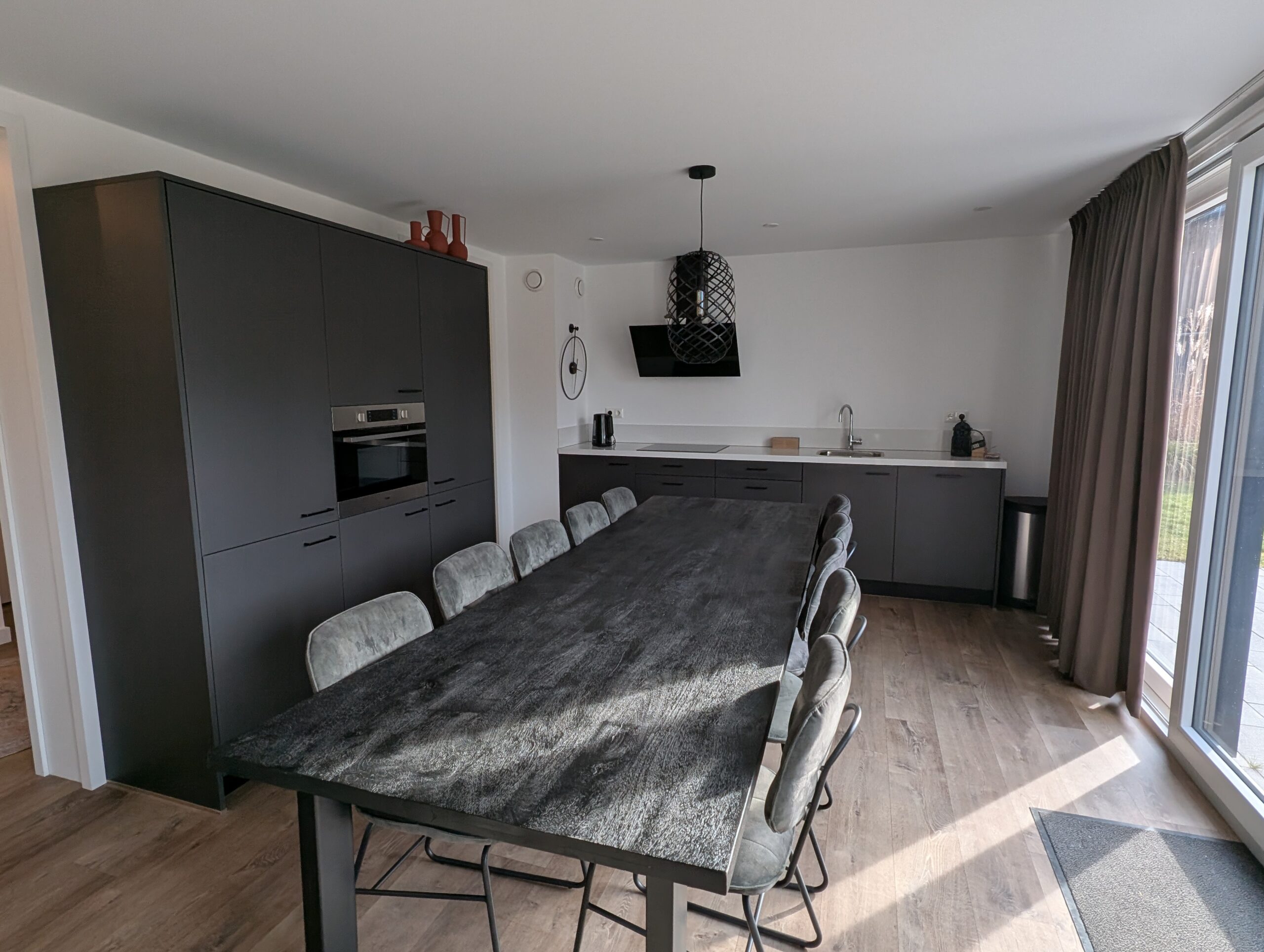 De lange eettafel met kast en keuken