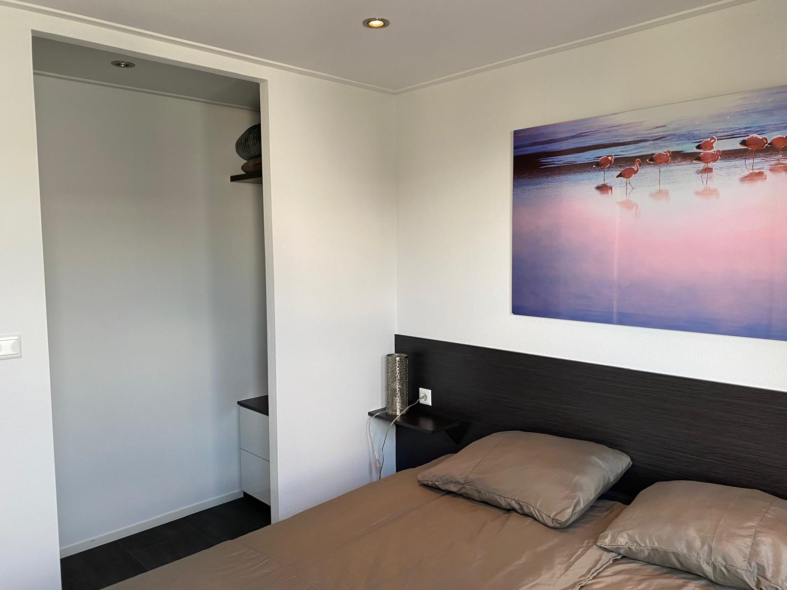 Een foto van de slaapkamer met tweepersoonsbed en een open kast